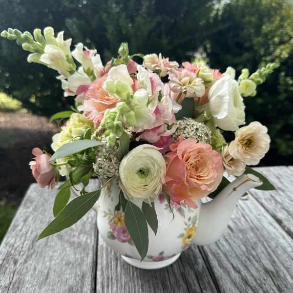 Pastel bouquet in a floral teapot vase