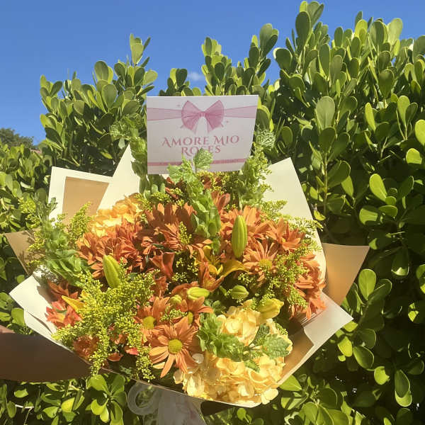 Bouquet of orange and yellow flowers with a pink sign