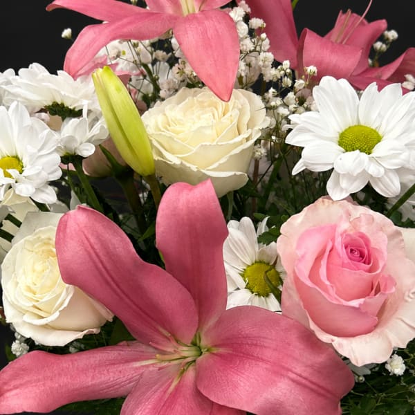 Pink lilies and roses with white daisies in a mixed bouquet