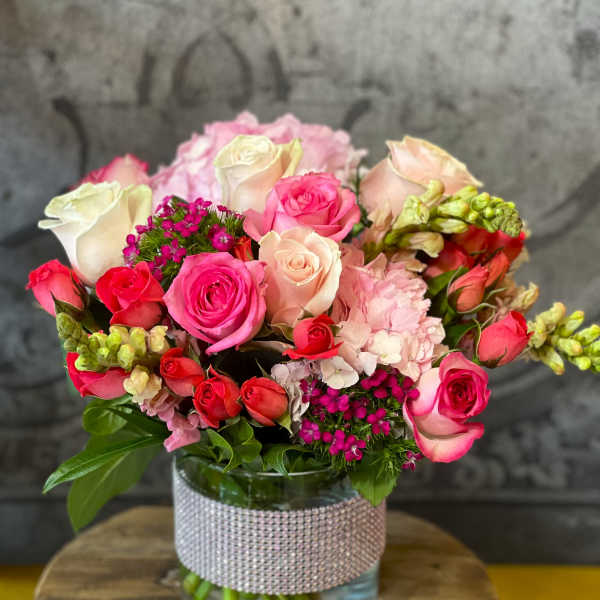 Bouquet of pink and white roses in a glass vase with a rhinestone wrap