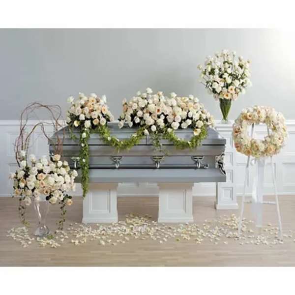 White floral funeral casket spray with matching wreath and standing arrangements