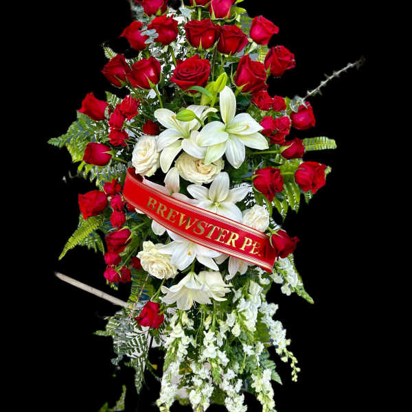 Standing floral spray of red roses and white lilies with a red ribbon