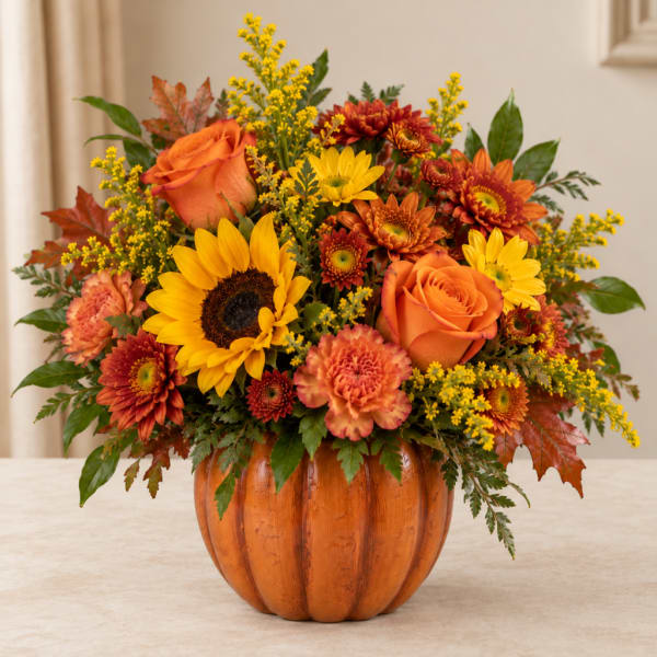 Autumn bouquet in a pumpkin-shaped vase with sunflowers, roses, and mums