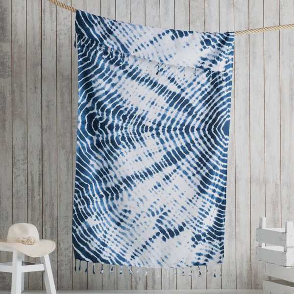 Blue and white patterned textile hanging on a rope against a wood wall