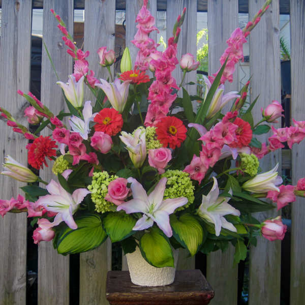 Tall bouquet of pink lilies, roses, and red gerbera daisies in a white vase
