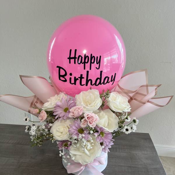 Pink birthday balloon above a pastel flower arrangement in a white box