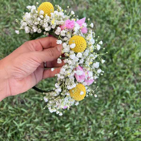 Handheld flower crown with white baby's breath, yellow blooms, and pink flowers