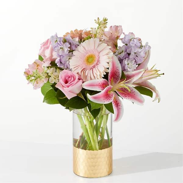 Pink and lavender bouquet in a clear vase with a gold base