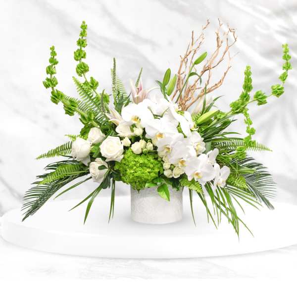 White orchids and roses in a white vase with bright green accents