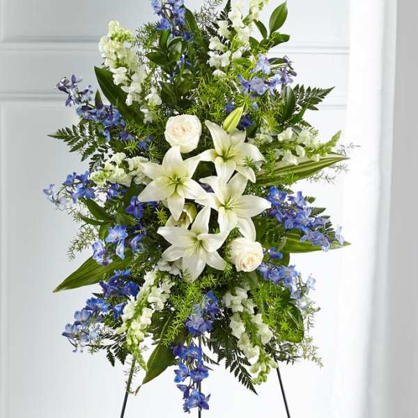 Standing floral spray with white lilies, white roses, and blue flowers