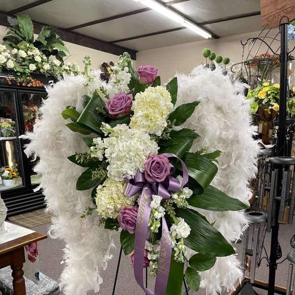 White and lavender floral standing spray with purple ribbon on an easel