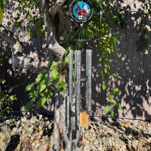 Wind chime hanging from a tree branch with a small bird ornament