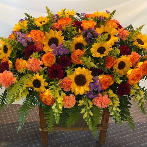 Large mixed flower arrangement with sunflowers, orange roses, and carnations