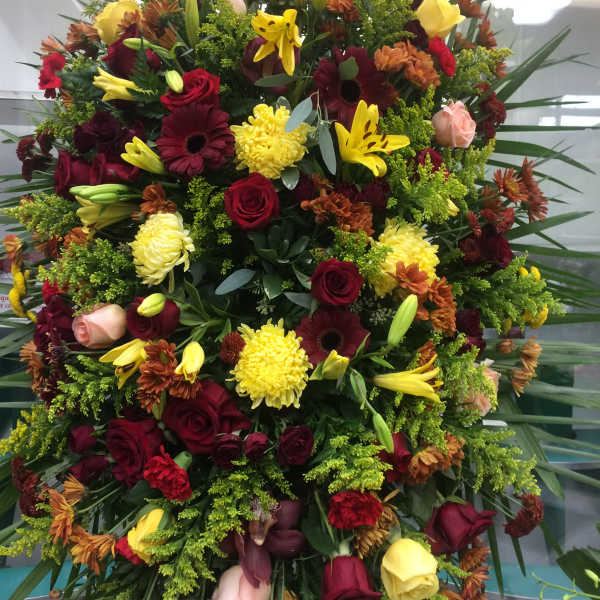 Large mixed floral spray with red, yellow, and peach blooms