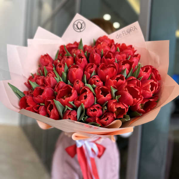 Bouquet of red tulips wrapped in pale pink paper