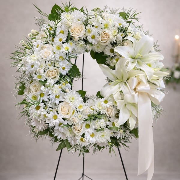 White floral wreath on a stand with a ribbon bow
