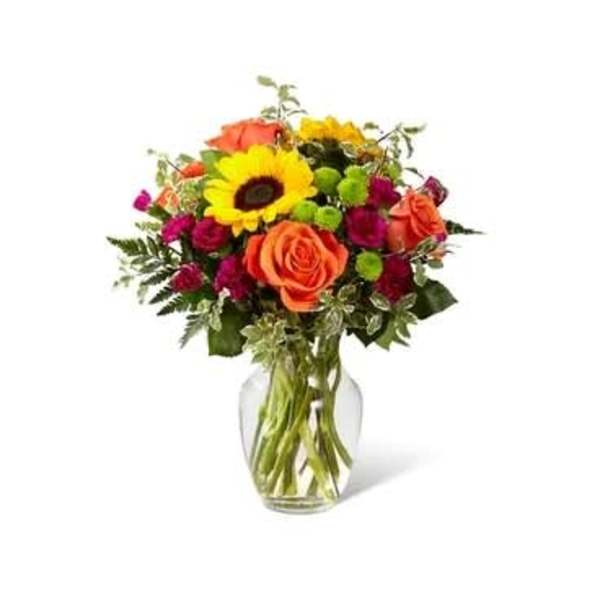 Bouquet of orange roses and a yellow sunflower in a glass vase