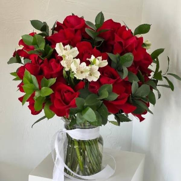 Bouquet of red roses with white flowers in a glass vase