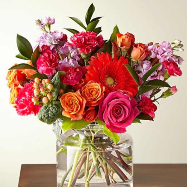 Bright mixed bouquet in a clear glass vase with roses and gerbera daisies