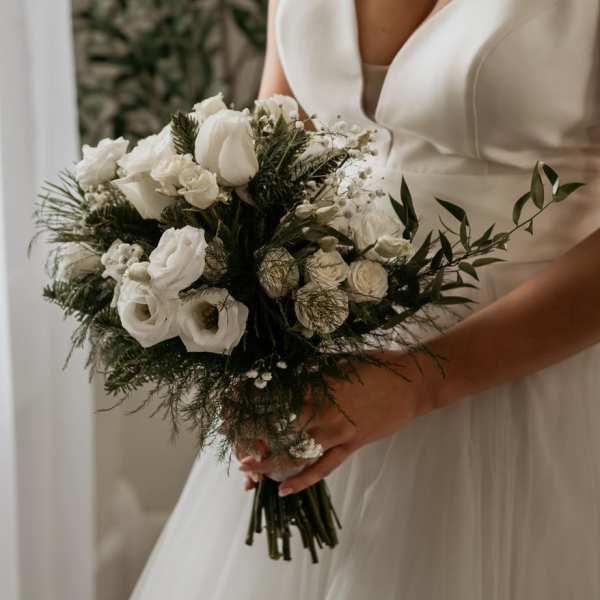 Bride holding a white bouquet with roses and small filler flowers