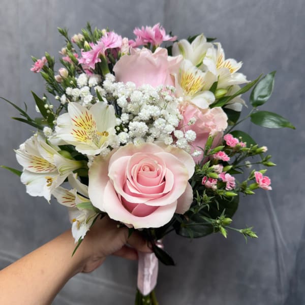 Handheld bouquet with pink roses, white lilies, and small pink filler flowers