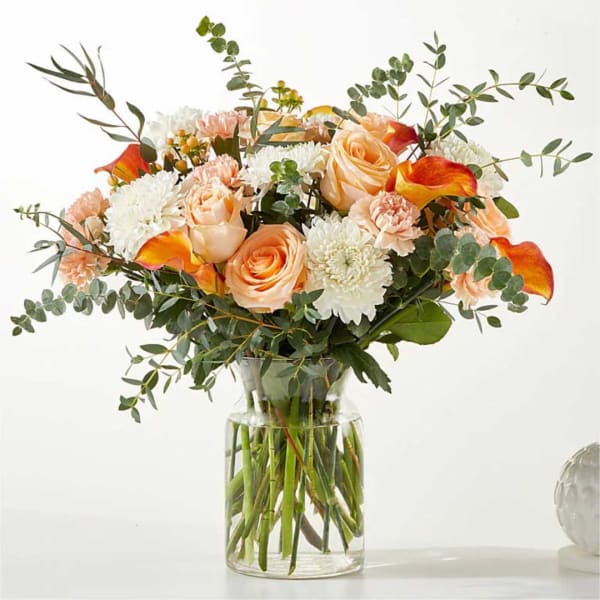 Peach roses and white mums in a clear glass vase