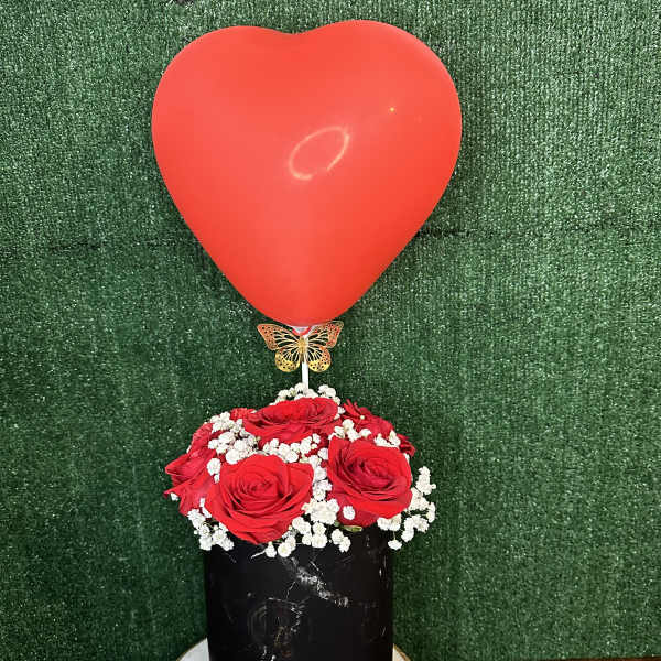 Red heart balloon above a box of red roses and chocolates