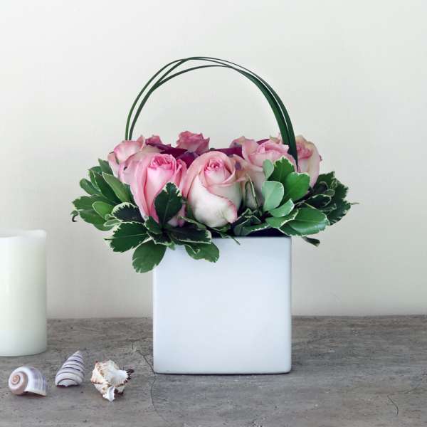 Pink roses in a white square container with a green handle