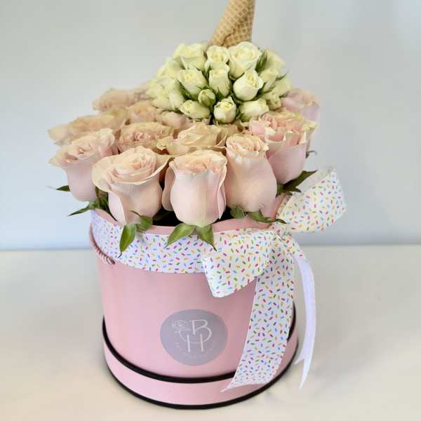 Pink rose arrangement in a round box with a decorative ribbon