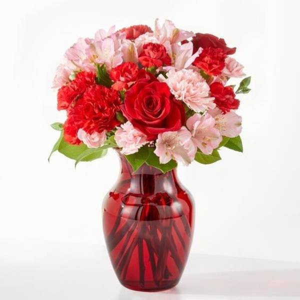 Red and pink flower bouquet in a red glass vase