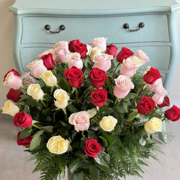 Bouquet of red, pink, and cream roses in a glass vase