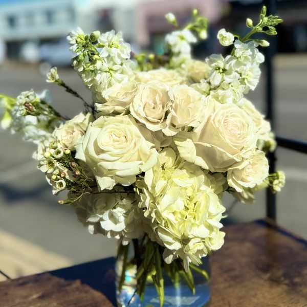 Bouquet of cream roses and white blossoms in a clear glass vase