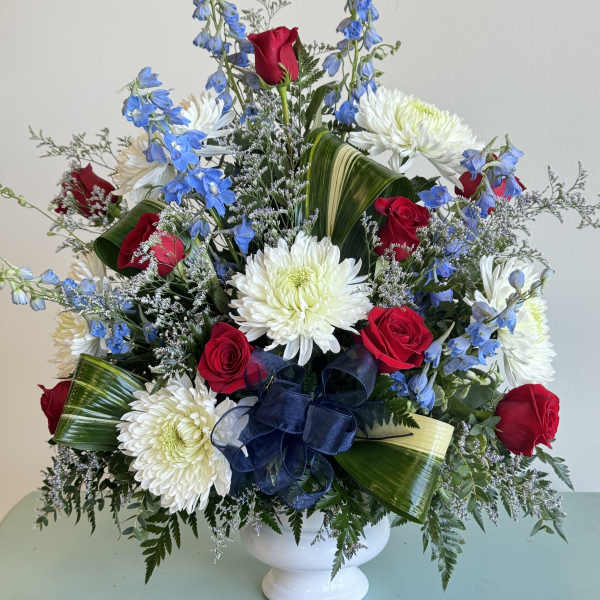 Red roses and white chrysanthemums in a white vase with blue flowers
