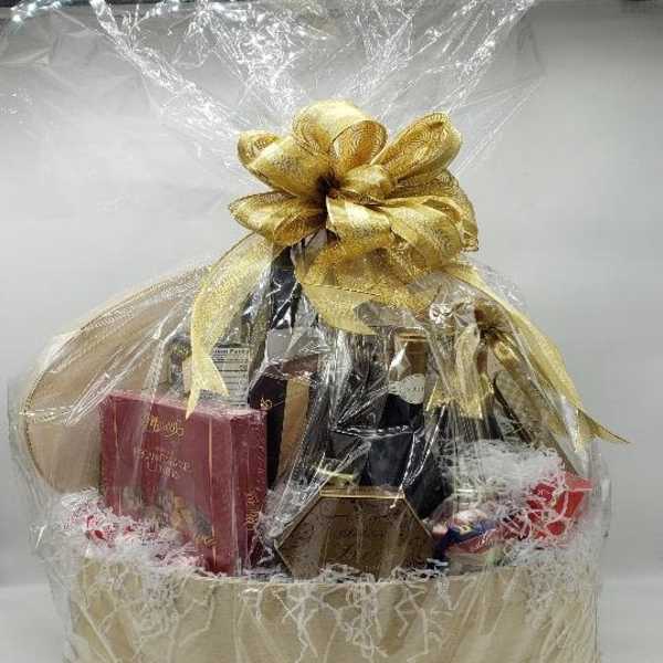 Gift basket with bottles and boxed treats wrapped in clear cellophane and a gold bow