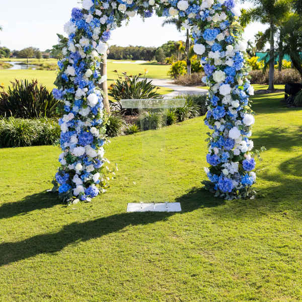Blue and white floral arch on a lawn outdoors