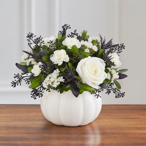 White floral arrangement in a white pumpkin-shaped vase