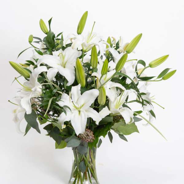 White lilies arranged in a clear glass vase