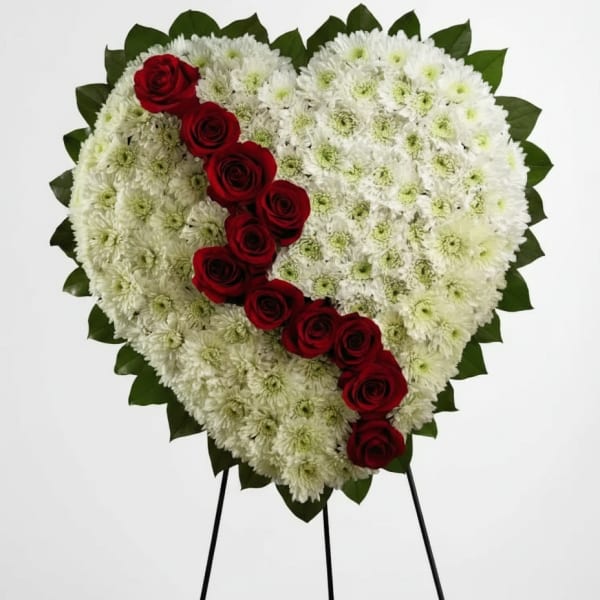 Heart-shaped white chrysanthemum wreath with red roses on a stand
