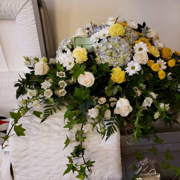 Large white and yellow funeral spray with roses, daisies, and hydrangea