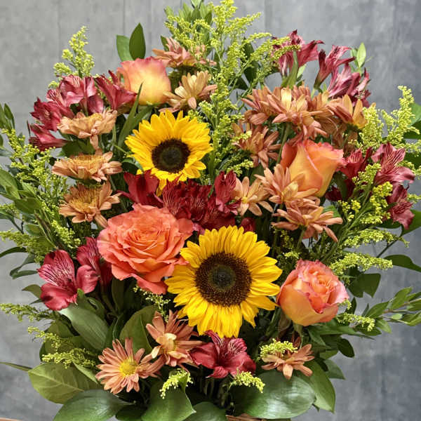 Basket arrangement with sunflowers, orange roses, and mixed blooms