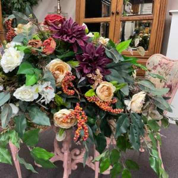 Large floral arrangement with roses, white blooms, and purple flowers in a stand