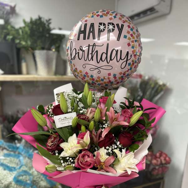 Pink birthday balloon above a bouquet of lilies and roses