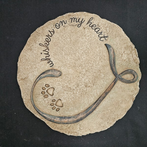 Round textured plaque with the words "whispers on my heart" and paw prints