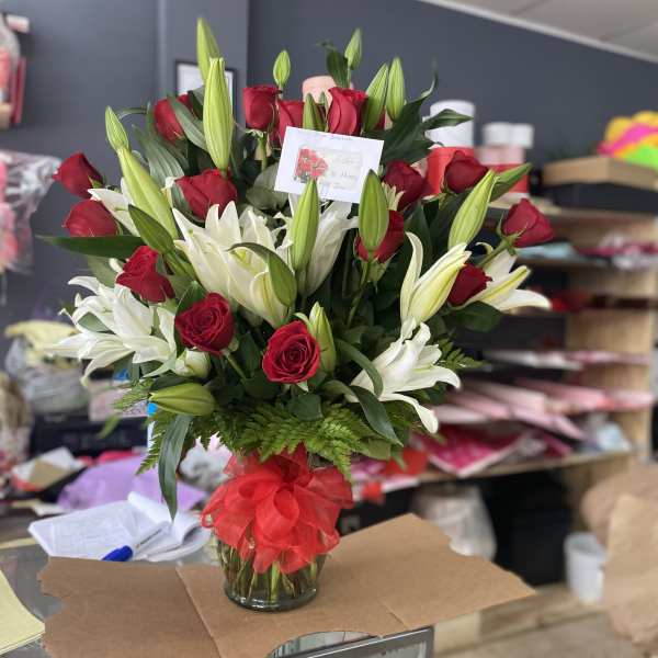 Red roses with lilies arrangement in vase
