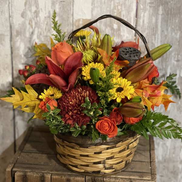 Autumn flower basket with orange roses and yellow mums in a woven basket