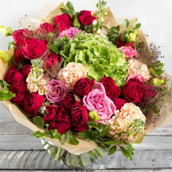 Bouquet of red and pink roses with green hydrangea in paper wrap