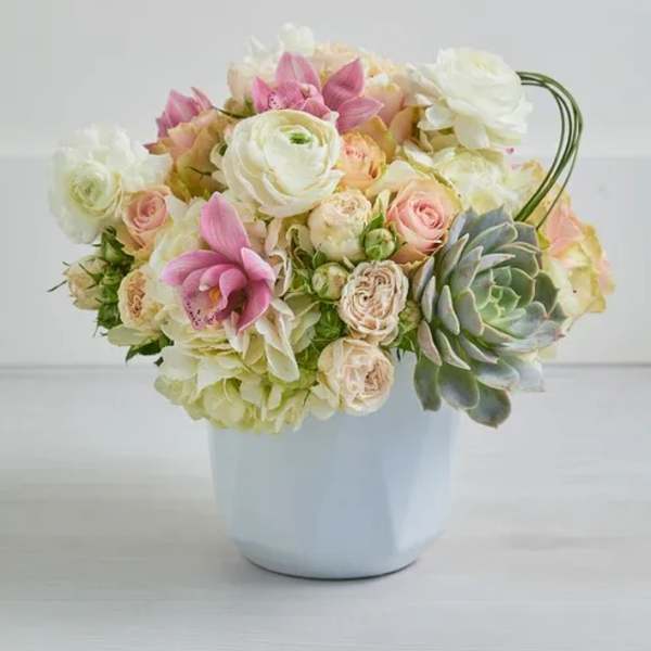 Pastel bouquet of roses, ranunculus, and orchids in a white vase