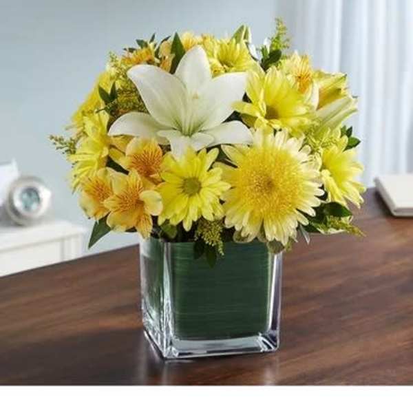 Yellow and white flower arrangement in a square glass vase