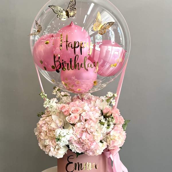 Pink birthday balloon above a pastel flower arrangement in a pink box