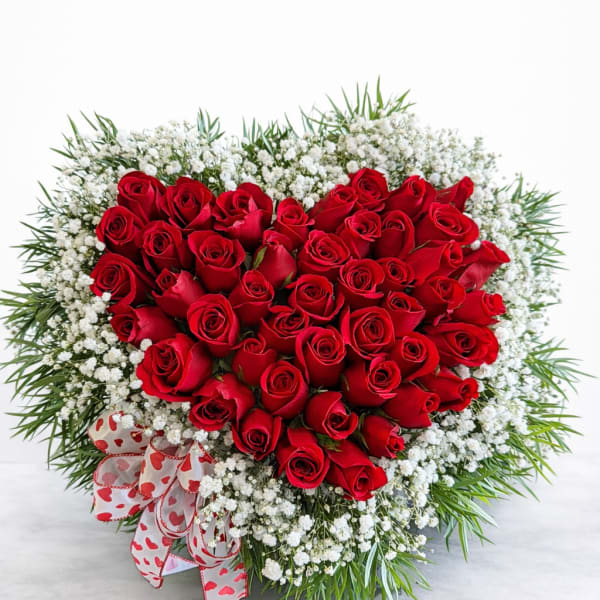 Heart-shaped bouquet of red roses with white baby's breath and a heart ribbon